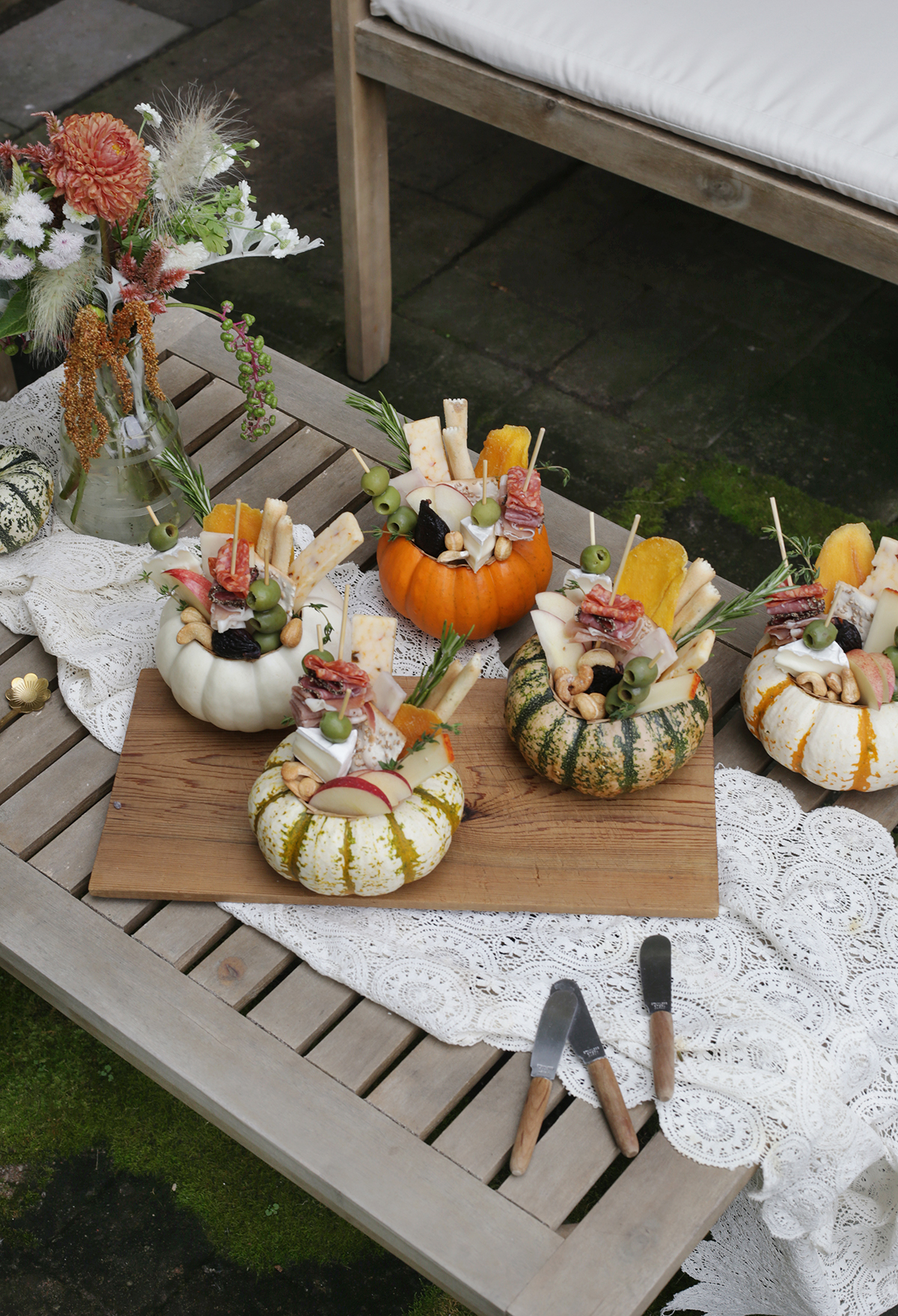 wooden slat table with lace runner scattered with mini pumpkin charcuteries
